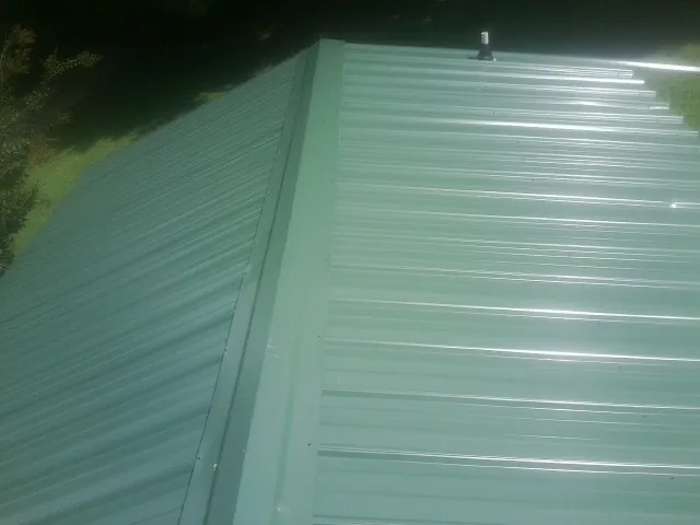 New green metal panels meeting at the ridge of a roof — Flat Roof Repair work by our crew in Bridgewater